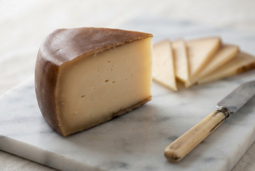 Idiazábal: dark brown smoked rind, compact beige paste, on a marble slab