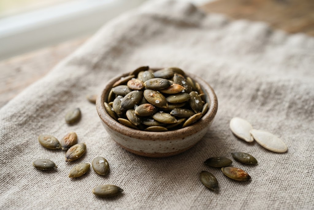 Pumpkin Seeds: flat oval dark olive-green pepitas, on natural linen